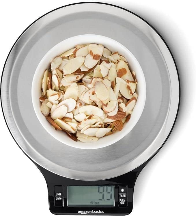 Sliced almonds in a bowl on digital kitchen scale for accurate weight measurement.