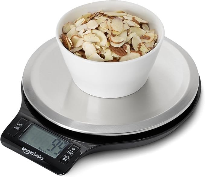 Fresh sliced almonds on digital kitchen scale for accurate weight measurement.