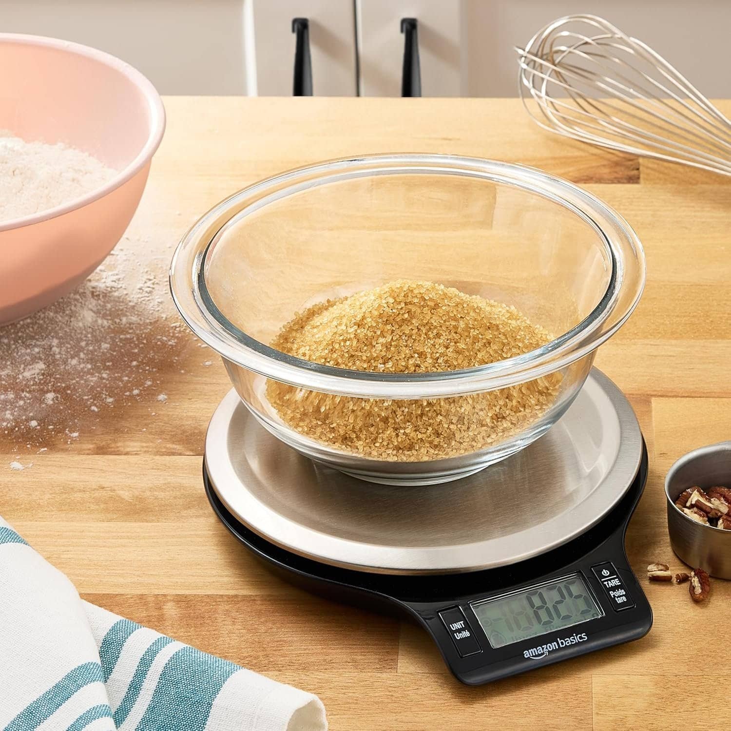 Digital kitchen scale measuring brown sugar on wooden countertop.