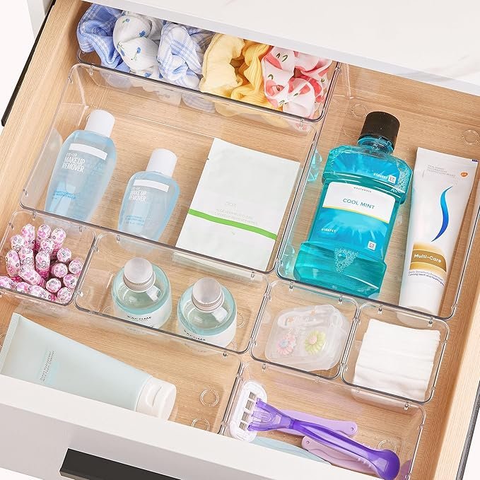 Clear drawer organizer with toiletries and skincare products for bathroom storage.