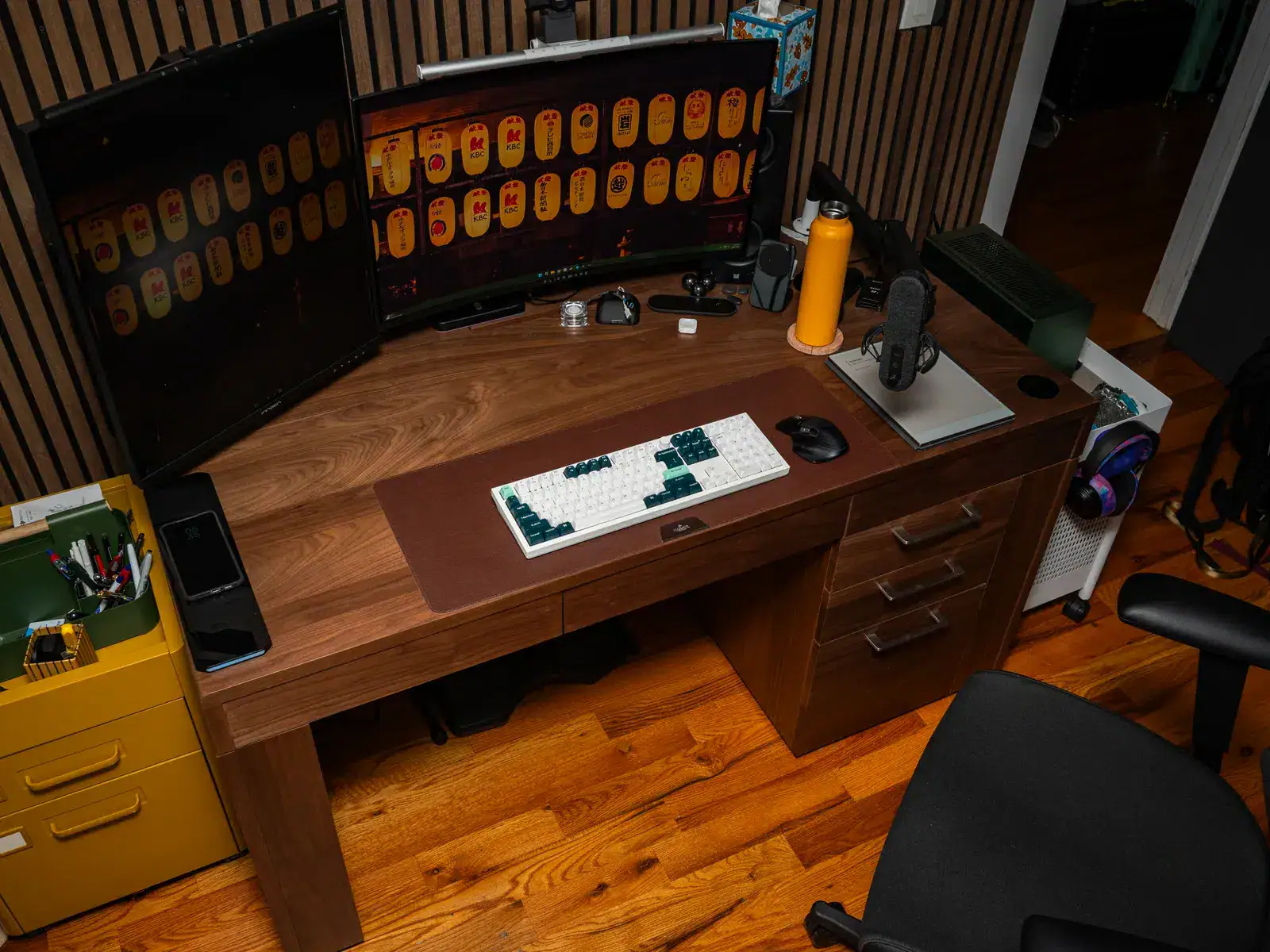 Triple monitor setup with keyboard, mouse, and tech accessories for gaming or productivity.