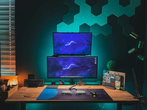 Dual monitor gaming setup with LED lighting and tech accessories.